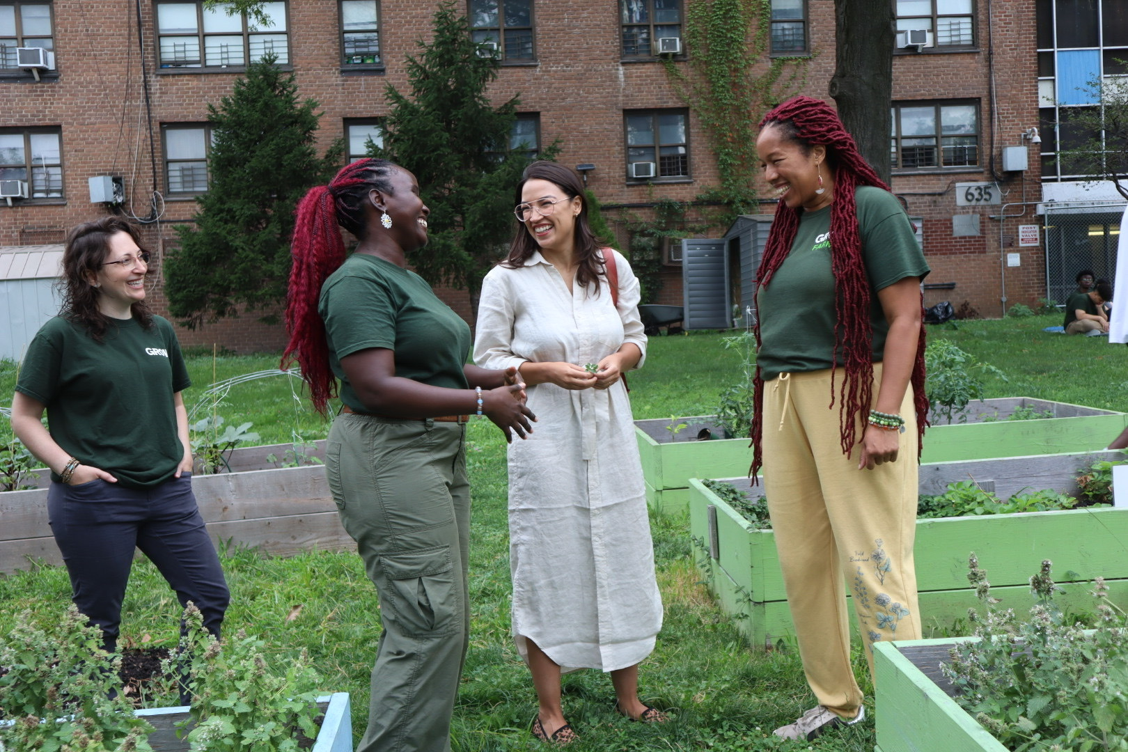 Rep. AOC laughs with 3 constituents in a community garden
